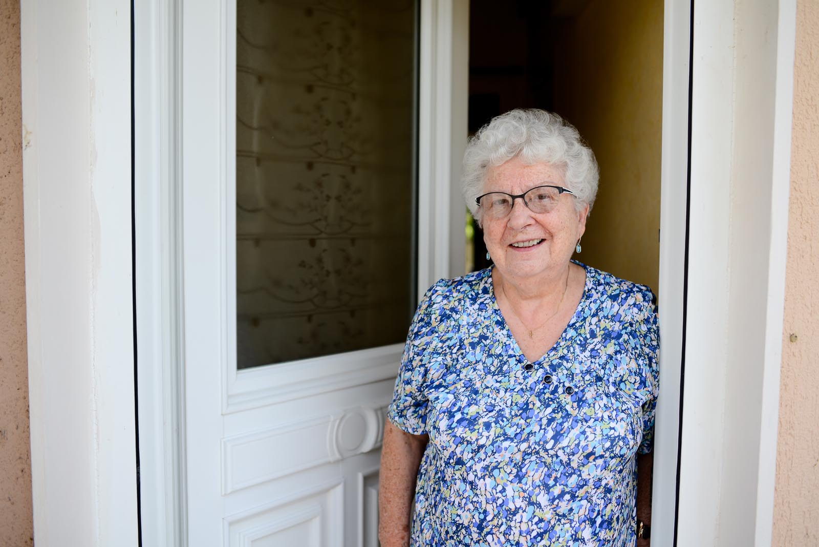Elderly woman leaning against the front door of her house